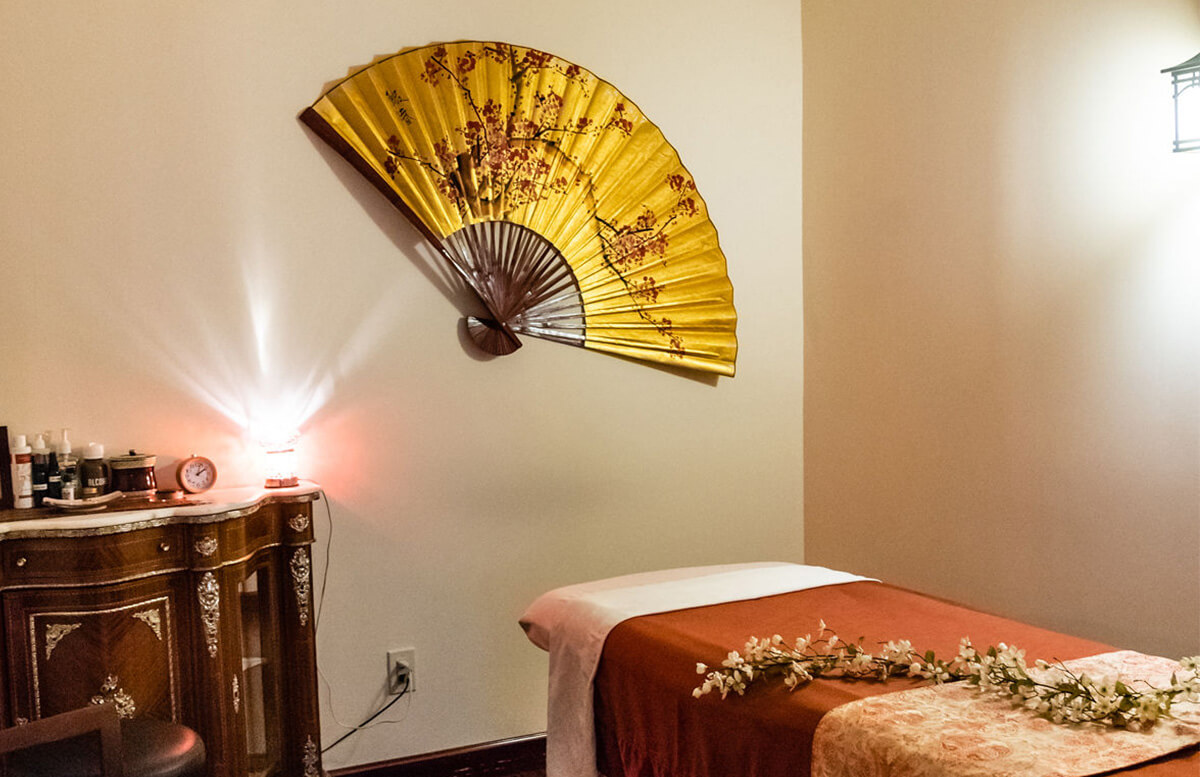 Serene massage room with a golden decorative fan and soft lighting.