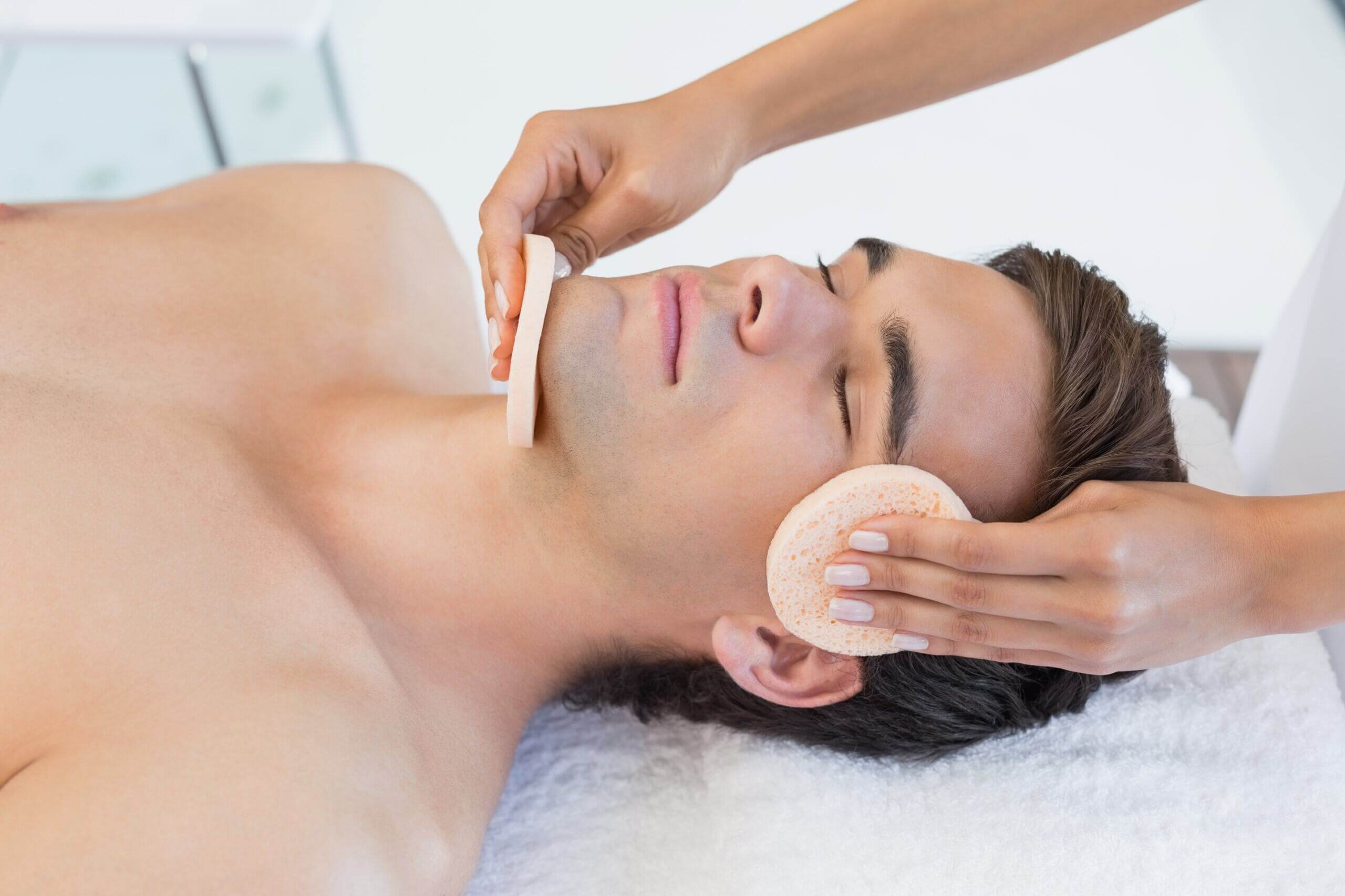 Therapist gently cleansing client's face with sponge Therapist gently cleansing client's face with sponge